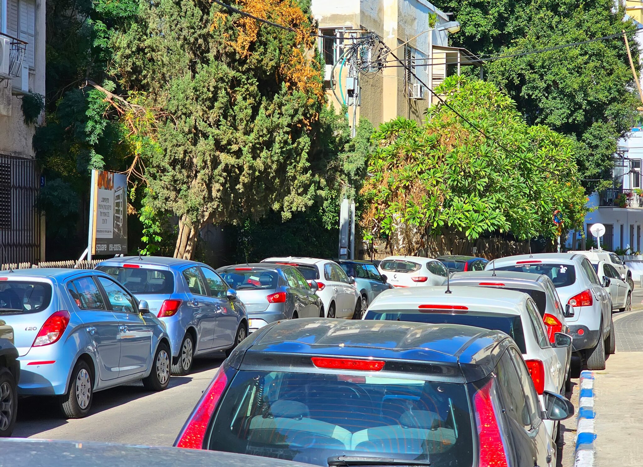 רחוב צר עם רכבים חונים בצפיפות וללא מרווח